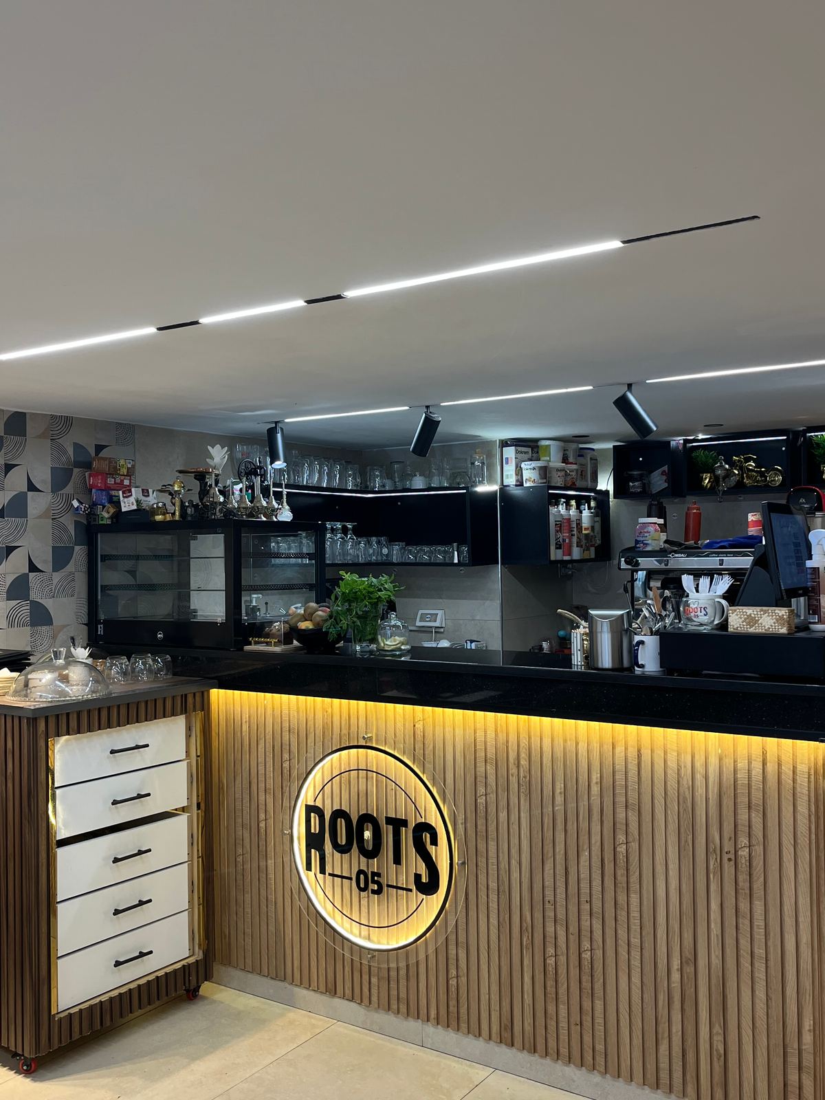 Le bar de Roots 05 et son logo rétroéclairé sur le mur en bois